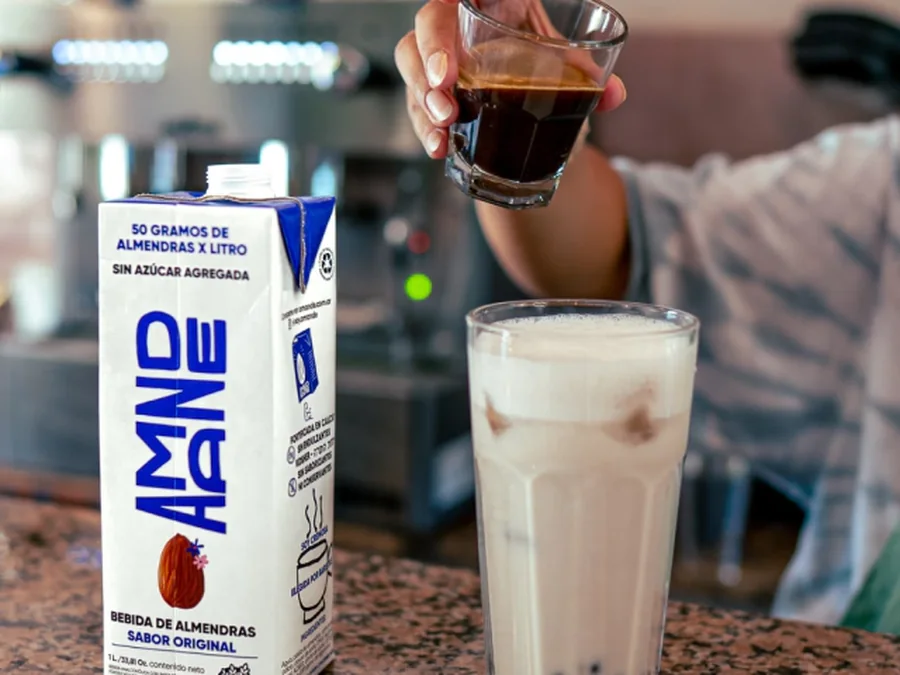 Envase de leche de almendras AMND junto a un vaso servido
