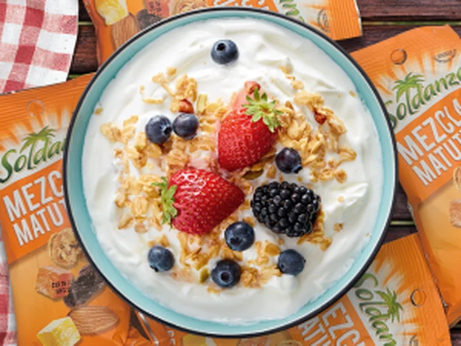 Bol de granola con frutos rojos junto a los envases de la marca