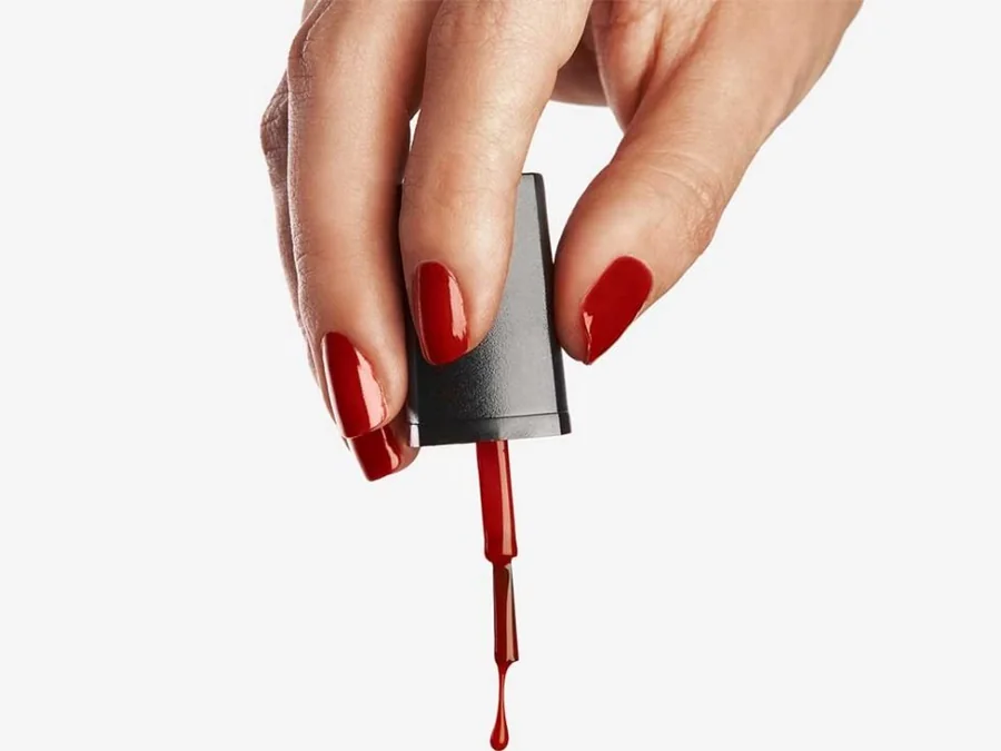 Frasco de esmalte CUVAGE volcándose sobre fondo blanco, con el hilo de esmalte y su reflejo